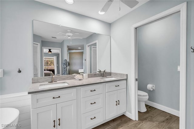 bathroom featuring wood-type flooring, vanity, ceiling fan, toilet, and a shower with door