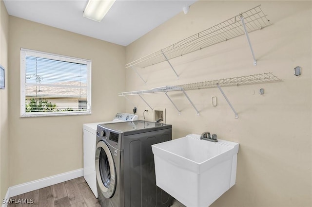 laundry room featuring independent washer and dryer, sink, and hardwood / wood-style floors