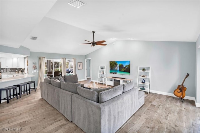 living room featuring lofted ceiling, sink, light hardwood / wood-style flooring, and ceiling fan