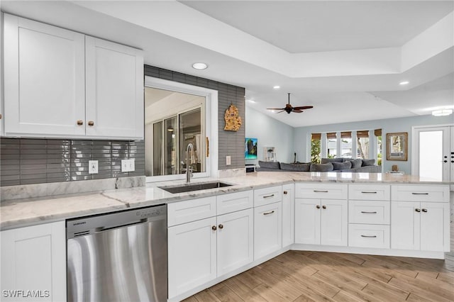 kitchen featuring stainless steel dishwasher, kitchen peninsula, sink, and white cabinets