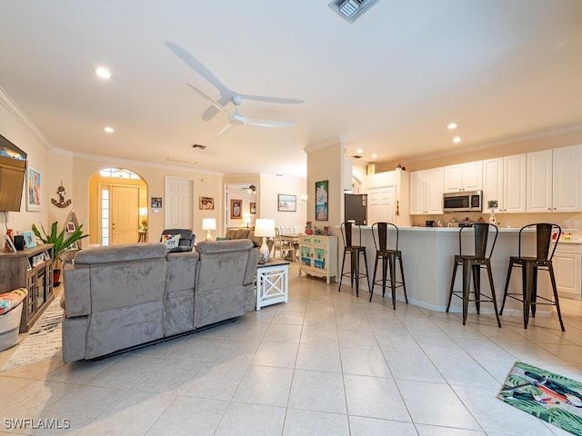 living room featuring crown molding, light tile patterned floors, and ceiling fan