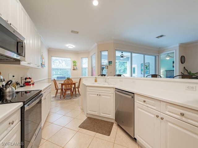 kitchen with appliances with stainless steel finishes, sink, light tile patterned floors, and white cabinets