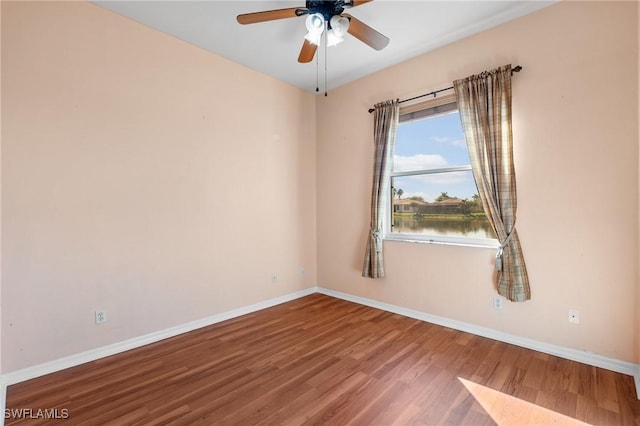 empty room featuring hardwood / wood-style flooring, a water view, and ceiling fan