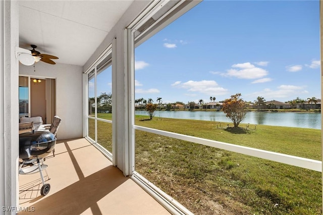 sunroom / solarium featuring a water view and ceiling fan