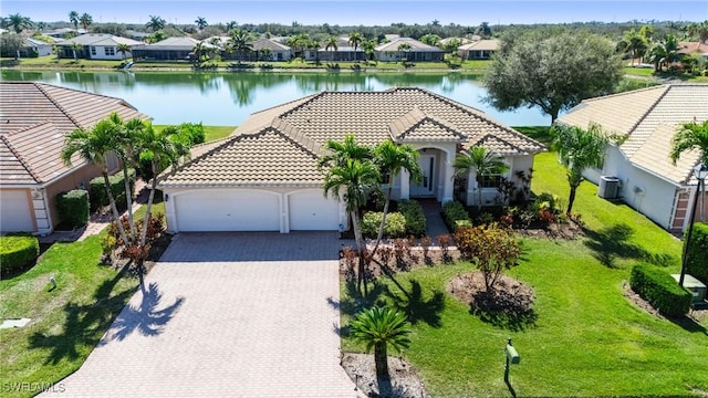 mediterranean / spanish-style home featuring a garage, a water view, cooling unit, and a front lawn