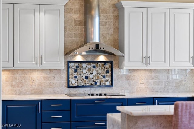 kitchen with black electric stovetop, white cabinets, blue cabinets, decorative backsplash, and wall chimney exhaust hood