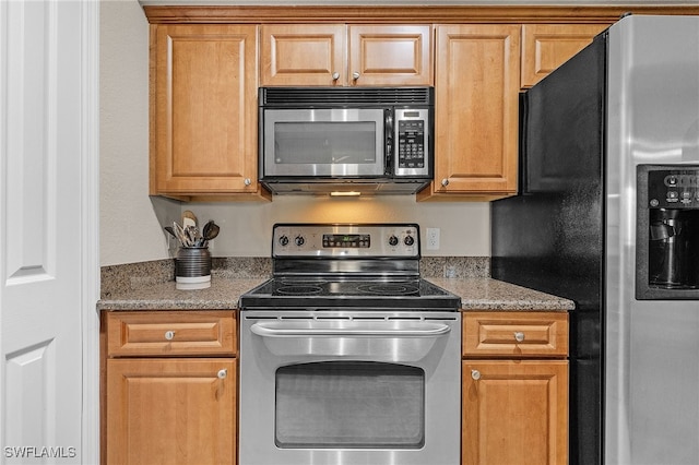 kitchen with appliances with stainless steel finishes and dark stone countertops