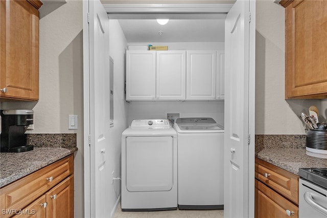 washroom with cabinets, washer and dryer, and light tile patterned floors