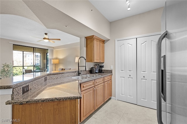 kitchen featuring sink, dark stone countertops, ceiling fan, kitchen peninsula, and stainless steel refrigerator with ice dispenser