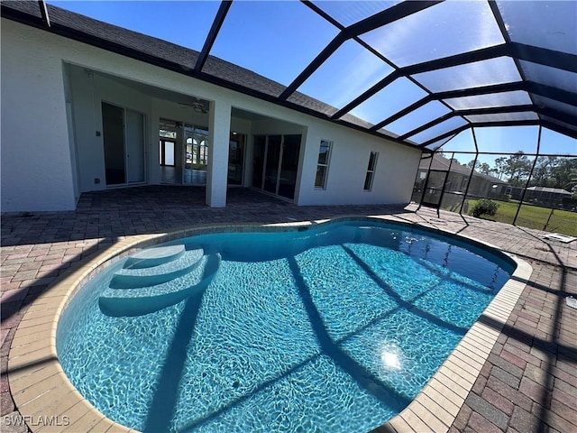 view of swimming pool featuring ceiling fan, a lanai, and a patio area