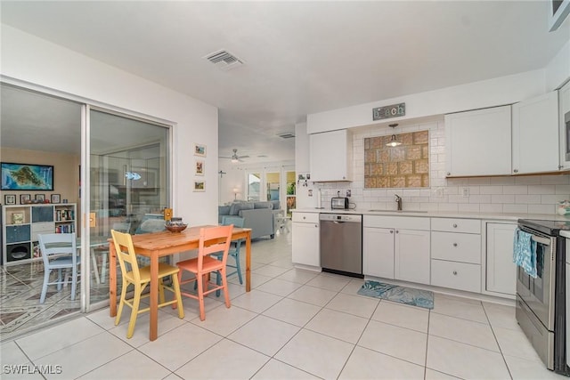 kitchen featuring sink, light tile patterned floors, appliances with stainless steel finishes, white cabinetry, and decorative backsplash