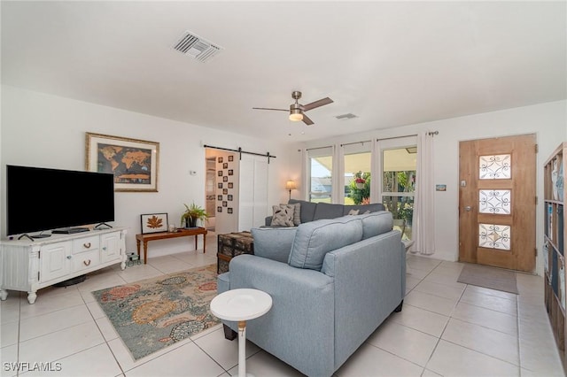 tiled living room featuring a barn door and ceiling fan