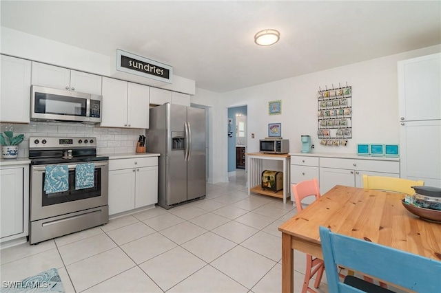 kitchen featuring white cabinetry, stainless steel appliances, tasteful backsplash, and light tile patterned floors