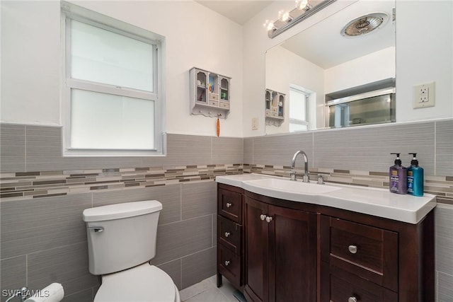 bathroom featuring vanity, toilet, and tile walls