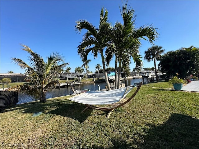 view of dock with a water view and a lawn