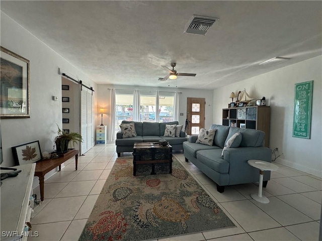 tiled living room featuring a barn door and ceiling fan