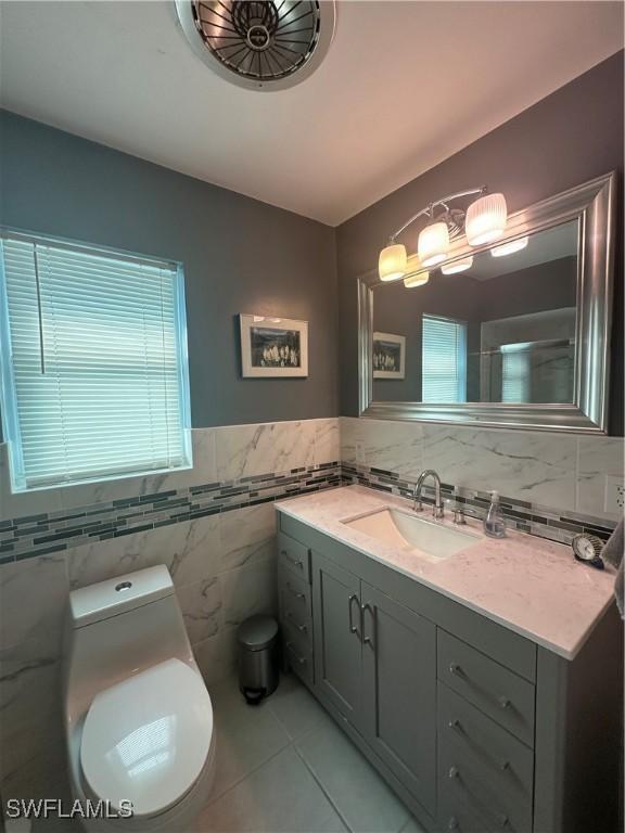 bathroom featuring vanity, tile walls, tile patterned floors, and toilet