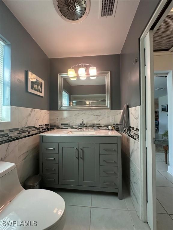 bathroom featuring tile walls, vanity, tile patterned flooring, and toilet