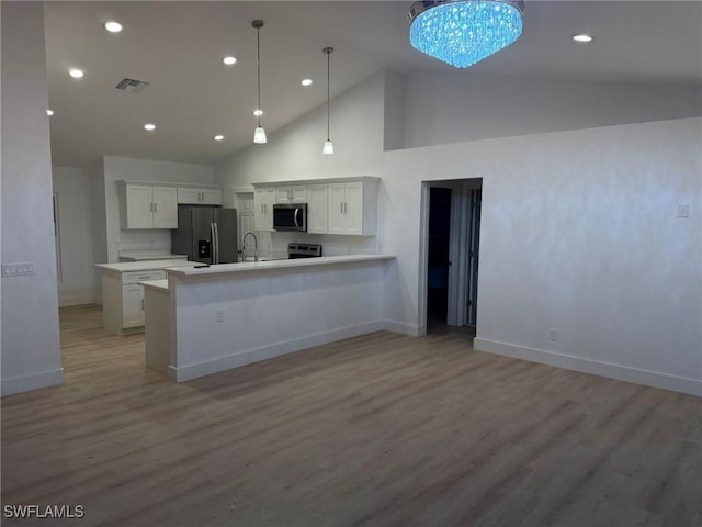 kitchen featuring pendant lighting, white cabinetry, sink, stainless steel appliances, and light hardwood / wood-style flooring