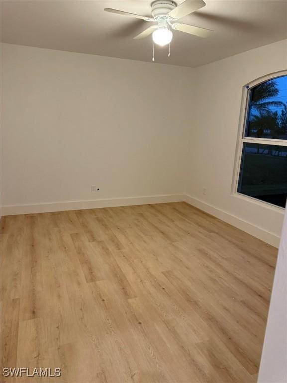 spare room featuring a ceiling fan, light wood-type flooring, and baseboards