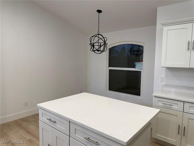 kitchen featuring hanging light fixtures, a center island, white cabinets, and light wood-type flooring