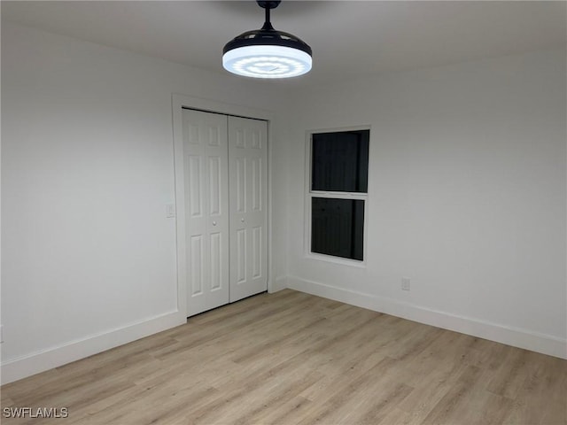 unfurnished bedroom with a ceiling fan, a closet, baseboards, and light wood finished floors