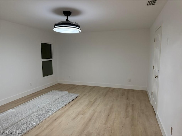 spare room with visible vents, light wood-style flooring, and baseboards