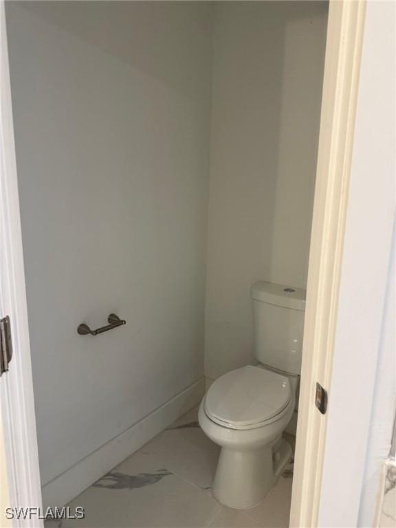 bathroom featuring marble finish floor, toilet, and baseboards