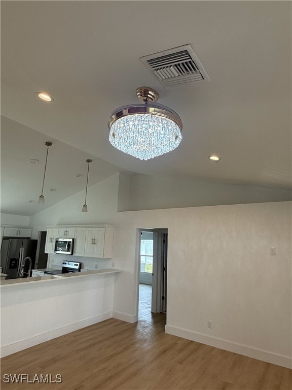 kitchen with lofted ceiling, stainless steel appliances, visible vents, light countertops, and light wood-type flooring