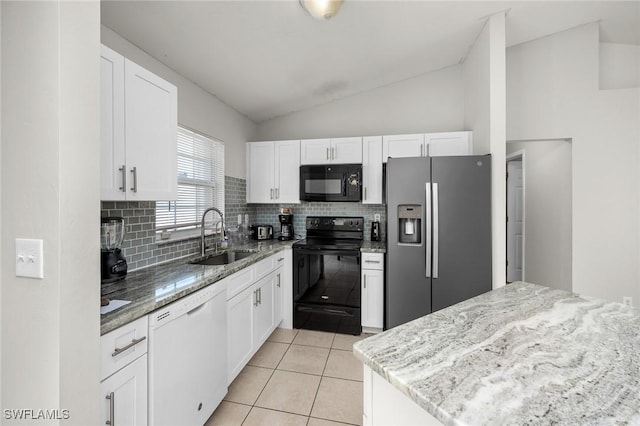 kitchen featuring vaulted ceiling, light tile patterned flooring, white cabinets, black appliances, and a sink