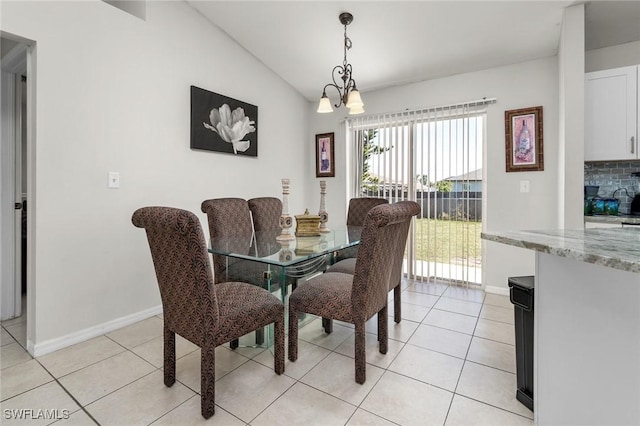 dining space with vaulted ceiling, a notable chandelier, light tile patterned floors, and baseboards