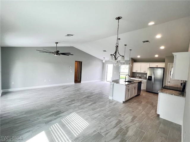 kitchen with stainless steel refrigerator with ice dispenser, white cabinetry, vaulted ceiling, a center island with sink, and pendant lighting