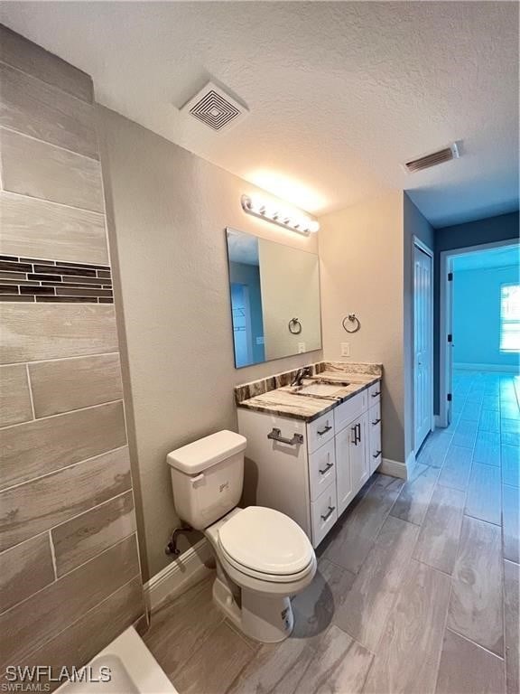 bathroom featuring vanity, a textured ceiling, and toilet