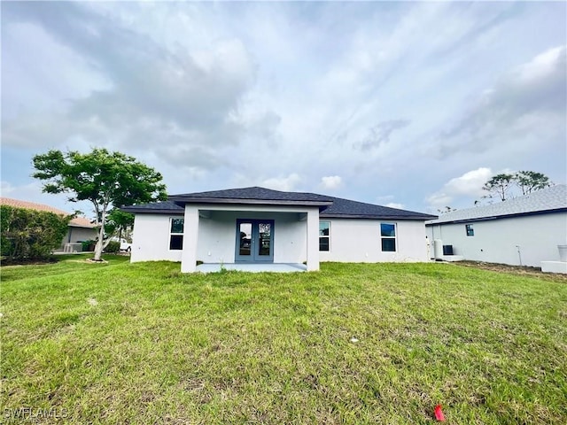 back of property with a lawn and french doors