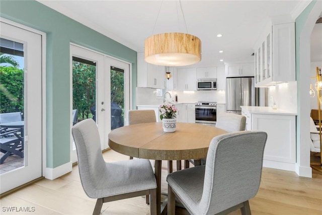 dining area with french doors, sink, and light hardwood / wood-style flooring