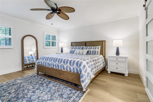 bedroom featuring ceiling fan, ornamental molding, a barn door, and light wood-type flooring