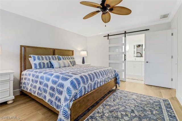 bedroom featuring hardwood / wood-style flooring, ornamental molding, and a barn door