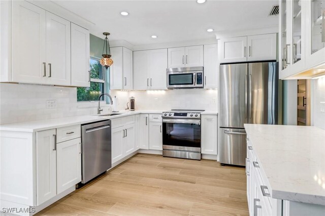 kitchen with stainless steel appliances, hanging light fixtures, sink, and white cabinets