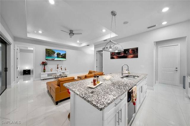 2330 6th Ave NE, Naples, FL 34120 - kitchen featuring sink, a center island with sink, a tray ceiling, pendant lighting, and white cabinets