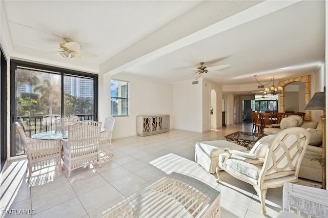 tiled living room featuring ceiling fan with notable chandelier