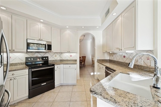 kitchen featuring appliances with stainless steel finishes, sink, white cabinets, ornamental molding, and light stone countertops