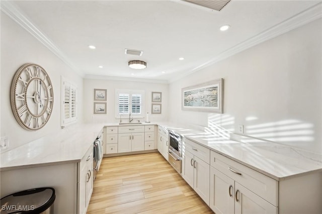 kitchen with white cabinetry, ornamental molding, light hardwood / wood-style flooring, and kitchen peninsula