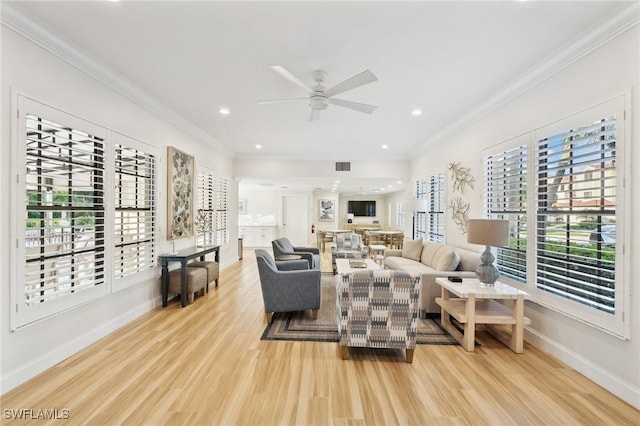 living room with ornamental molding, ceiling fan, and light wood-type flooring