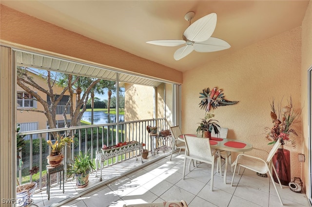 sunroom with ceiling fan and a water view