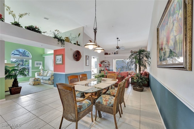 tiled dining space featuring ceiling fan and high vaulted ceiling