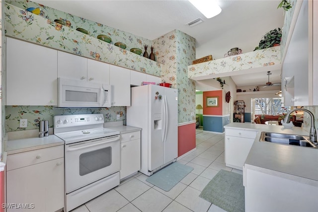 kitchen with sink, white appliances, light tile patterned floors, ceiling fan, and white cabinets