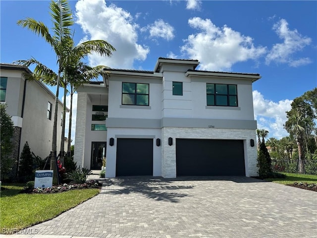 contemporary house featuring stucco siding, decorative driveway, an attached garage, and fence