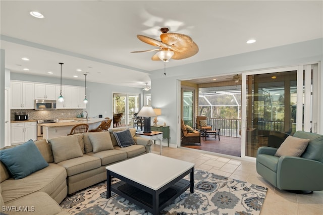 tiled living room with ceiling fan and sink