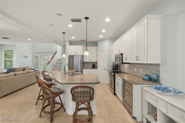 kitchen with pendant lighting, white cabinetry, an island with sink, and appliances with stainless steel finishes