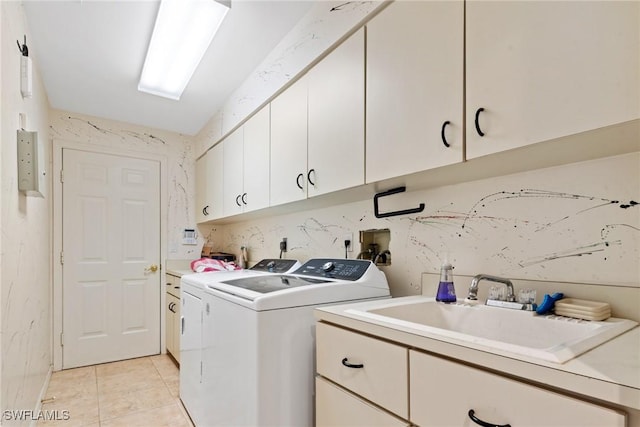 laundry area with cabinet space, washing machine and dryer, light tile patterned floors, and a sink